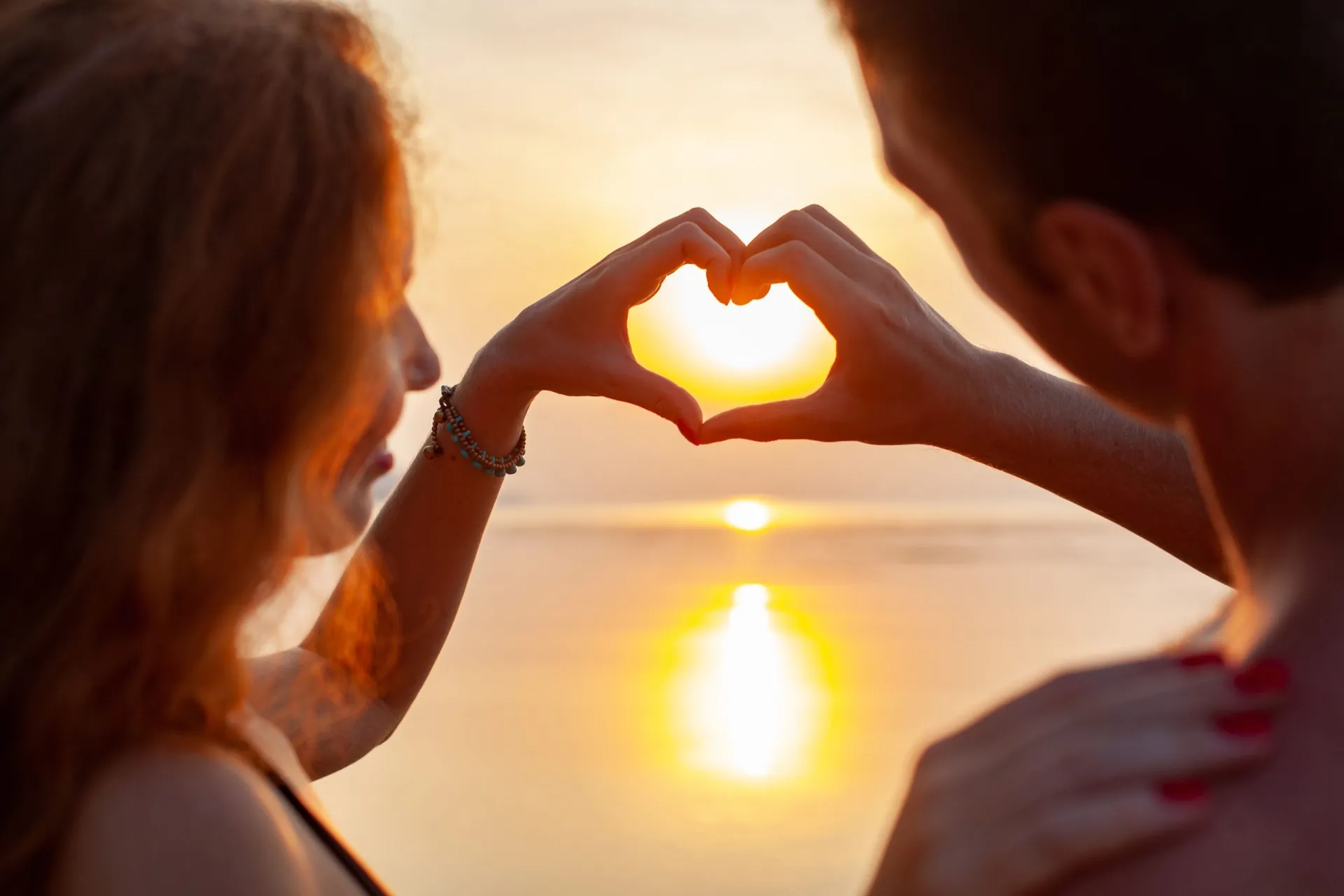young-sexy-romantic-couple-in-love-happy-on-summer-beach-together-having-fun-wearing-swim-suits-showing-heart-sign-on-sundet-scaled.jpg