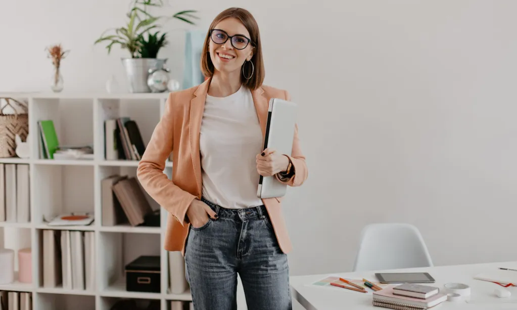 satisfied-female-entrepreneur-posing-with-laptop-hand-against-her-minimalistic-office-scaled.jpg